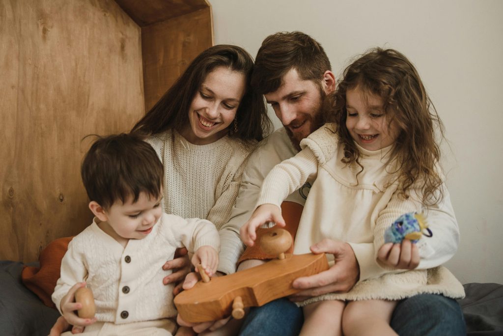 A joyful family of four playing together with a wooden toy indoors. Captures warmth and togetherness.