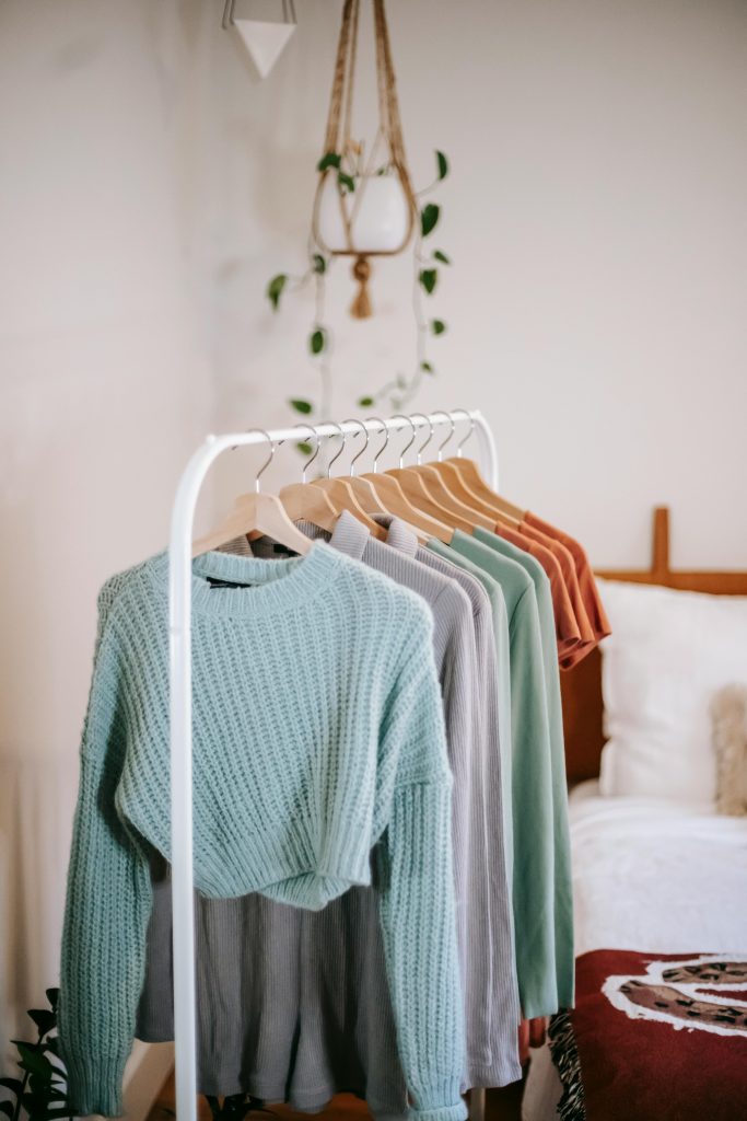 Chic bedroom interior featuring a stylish clothing rack with cozy sweaters in earthy tones.