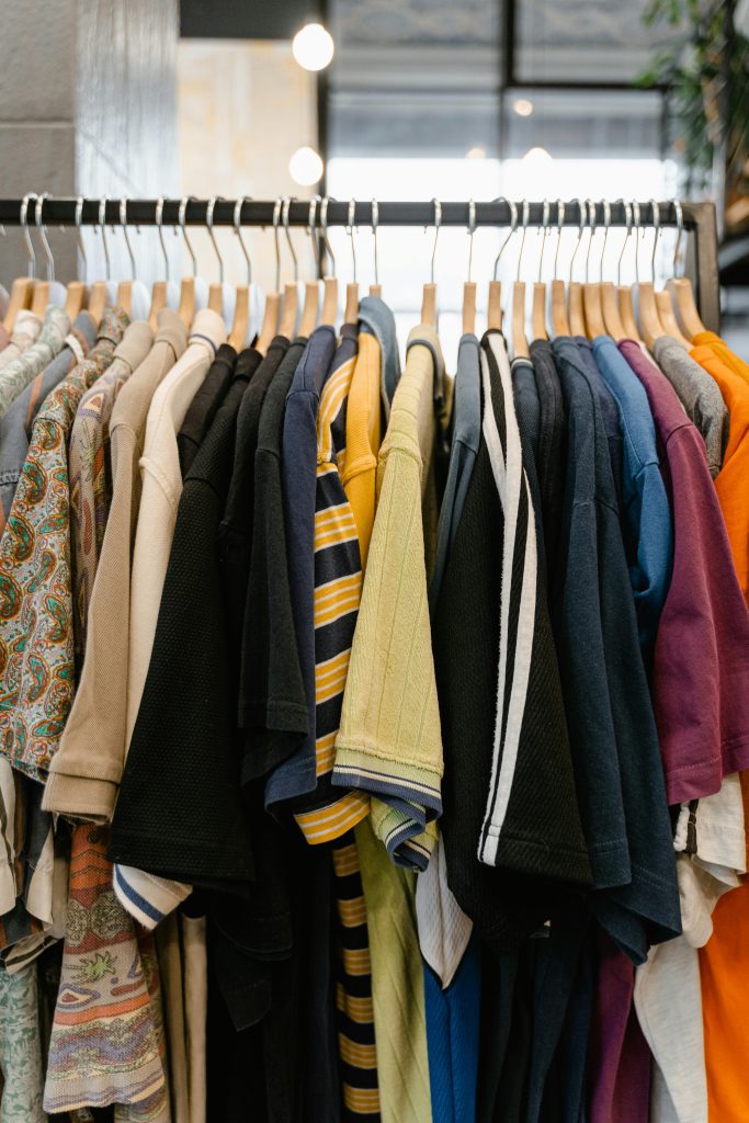 A variety of colorful t-shirts neatly arranged on a clothing rack indoors.